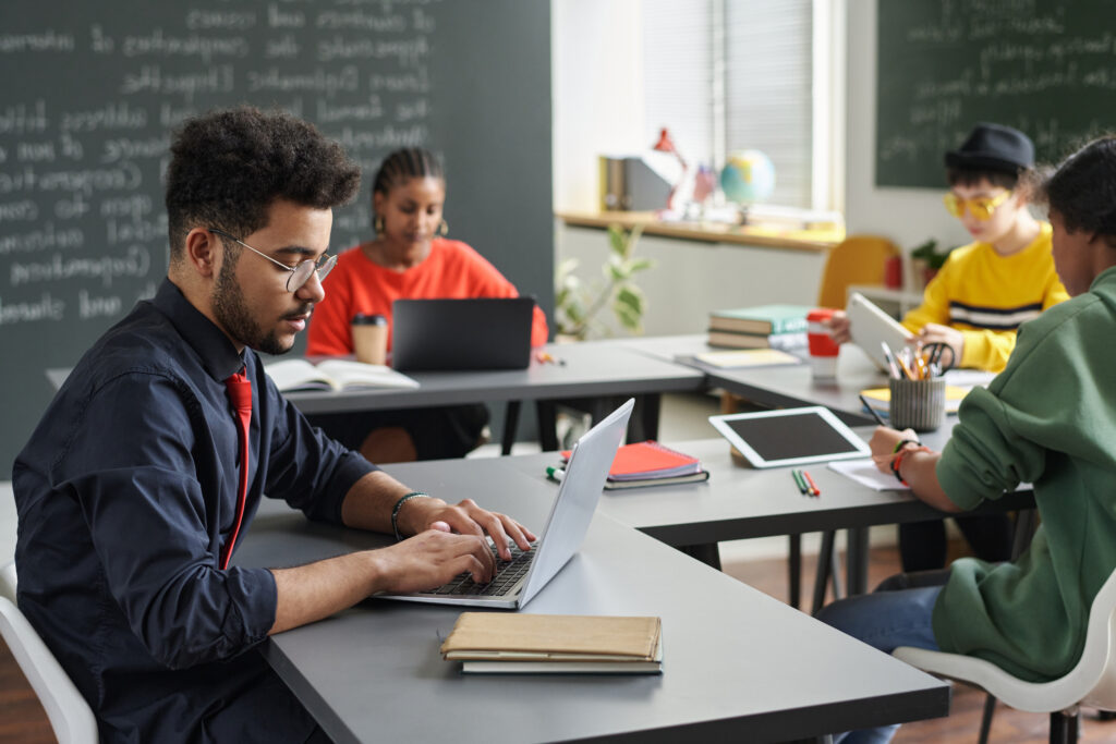 male teacher using laptop side view